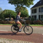 Young Dutch woman with phone on bike